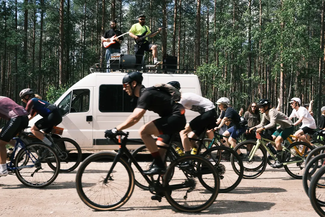 A group of FURY ROAD participants drives past a camp in a pine forest