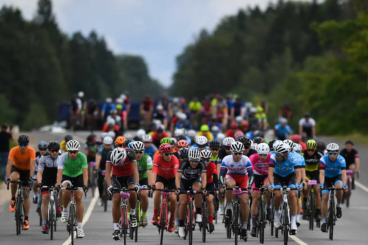 Gran Fondo Russia peloton rides along the road between the forests