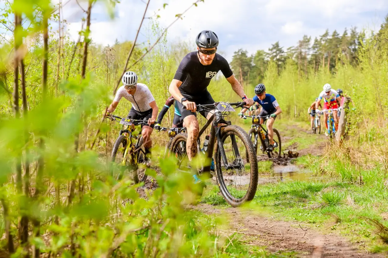 Participants of the Moscow bike marathons on the trail among green trees