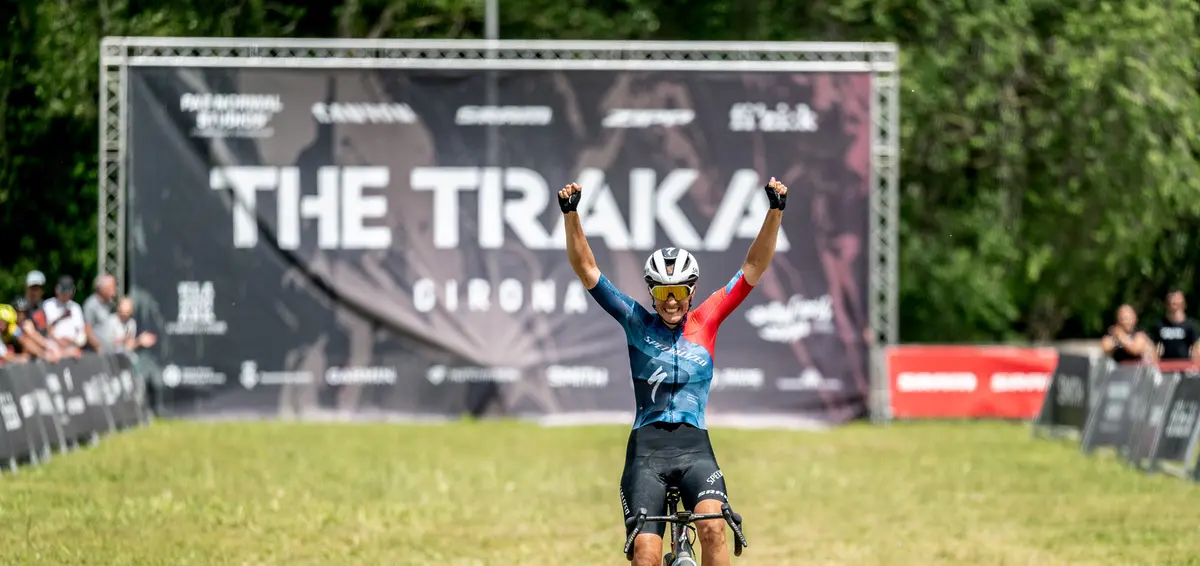 Racer celebrates the finish under the banner The Traka Girona