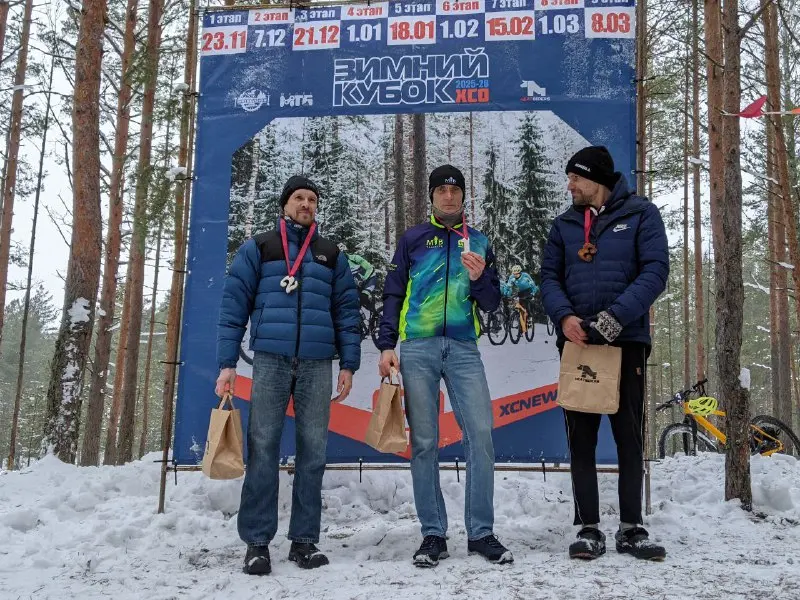 The winners of the XCnews winter MTB race on a pedestal in a snowy forest